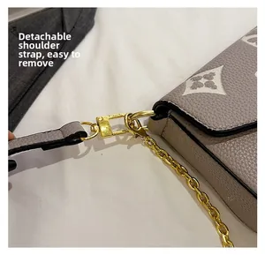 Detail of beige textured leather handbag with white floral monogram and detachable strap