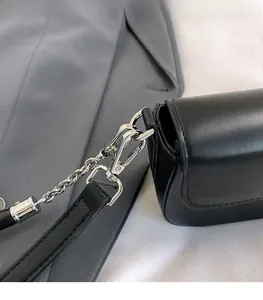 Close-up of silver metal clasp and chain strap detail on a black leather shoulder bag