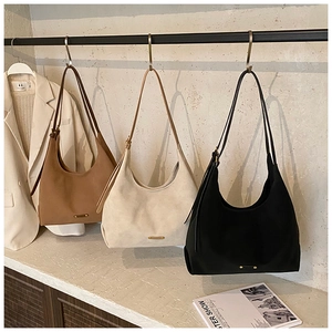 Close-up of minimalist hobo bags in brown, beige, and black on a display rack