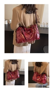 Détail d'un grand sac cabas en cuir PU rouge foncé avec plis latéraux et rivets en métal