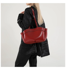 Side view of large burgundy leather tote bag with unique wavy top and contrast stitching
