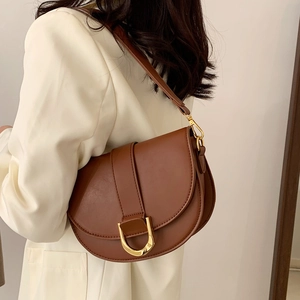 Sac besace en cuir marron avec boucle dorée porté avec un blazer beige chic