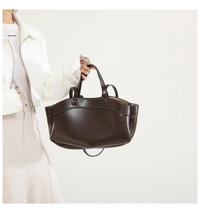 Detailed view of dark brown leather tote bag with white contrast stitching and twin handles