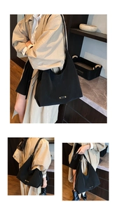 Detail showing the large capacity black tote bag with gold hardware worn by model