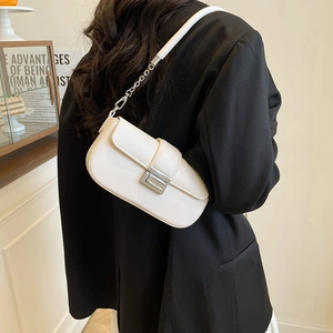 Close-up of cream white crossbody bag with silver metal buckle and chain strap on a black blazer