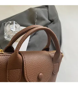 Detailansicht der braunen Ledertasche mit Litschi-Muster, Tragegriff und Metallreißverschluss
