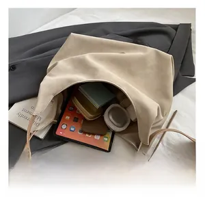 Spacious interior of a beige suede tote bag showing tablet and cosmetic storage capacity