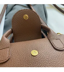 Detail einer braunen Handtasche mit Litschi-Maserung und goldenem Magnetverschluss