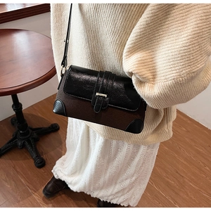 Detail of vintage bi-color shoulder bag featuring metal buckle and premium textures