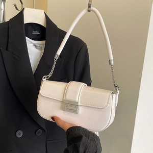 Detail of minimalist cream-colored baguette bag with silver geometric buckle on black suit