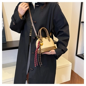 Detailed view of a retro beige and brown shell bag with a heart charm on a black coat