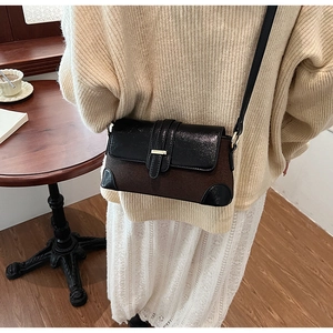 Close-up of retro color-block shoulder bag with gold clasp and textured brown suede