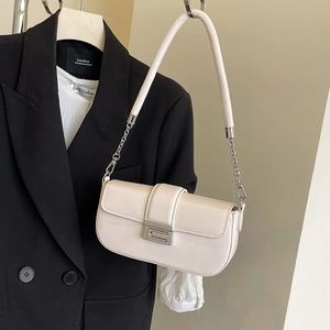 Close-up of cream patent leather bag with silver buckle and chain strap on blazer