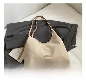 Close-up of off-white matte bucket bag with metal logo on elegant gray blazer