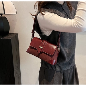 Detail of burgundy vintage shoulder bag featuring flap closure and leather strap