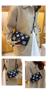 Detail of crossbody bag with white clover pattern and gold chain strap on black leather