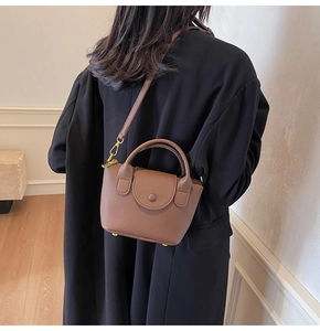 Detail der kaffeebraunen Mini-Handtasche aus genarbtem Leder mit goldenen Standfüßen