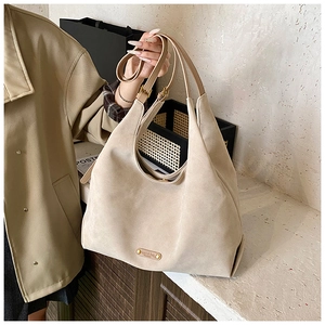 Detail of matte beige bucket bag showing suede texture, gold buckle, and wide strap