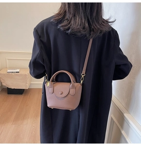 Rückansicht eines Modells mit brauner Handtasche aus Leder mit goldfarbenen Metallteilen