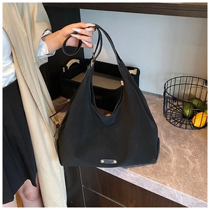 Detail of a black large capacity tote bag with adjustable shoulder strap and metal logo