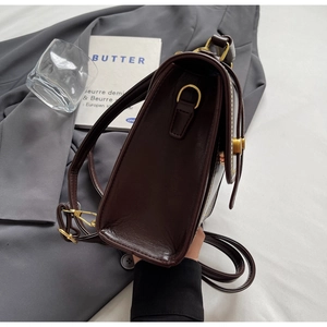 Detailed side view of vintage dark brown leather shoulder bag with gold D-ring hardware