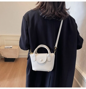 Detail einer weißen Mini-Tasche aus Leder mit Lychee-Narbung und goldenen Schnallen
