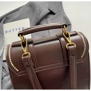 Detail view of deep brown PU leather handbag with golden hardware and stitching