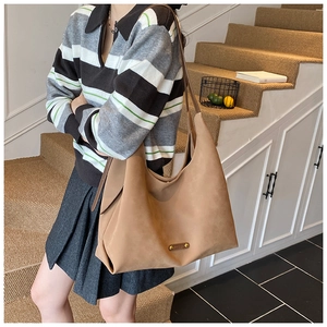 Model wearing a large khaki matte suede bucket bag with soft pleated texture