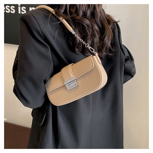 Detail of beige leather baguette bag with silver buckle and chain strap on a black blazer