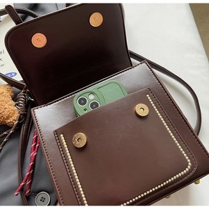 Detail view of dark brown vintage flap bag showing interior capacity with a mobile phone