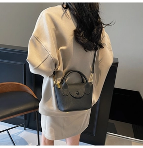 Detailansicht der schwarzen Handtasche aus Leder mit Goldbeschlägen und rundem Griff