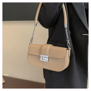 Model wearing a chic beige underarm bag with silver chain strap and metal clasp