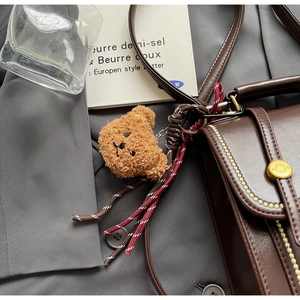 Detail of vintage brown leather handbag with teddy bear charm and metal buckle design