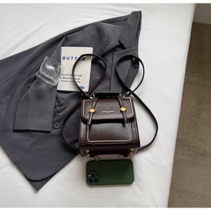 Flat lay of a vintage brown leather backpack with gold clasp and stylish accessories