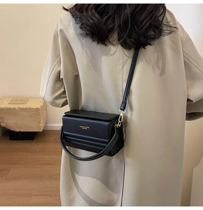 Detailed view of a black leather box bag featuring a stepped embossed texture and flap