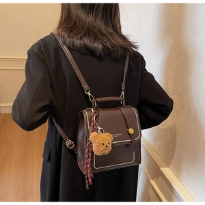 Detail of vintage brown leather backpack worn with black coat in home setting