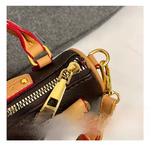 Détail du sac Boston en cuir marron foncé avec fermeture éclair dorée et bordure rouge