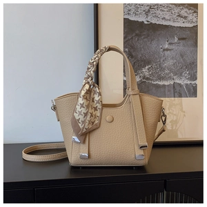 Detail of beige lychee leather handbag featuring houndstooth silk scarf and silver hardware