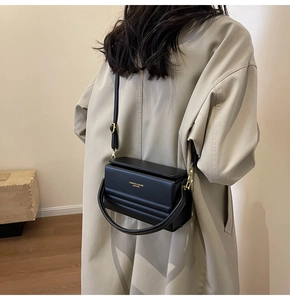 Detail of black matte leather box bag with gold metal hardware and detachable strap
