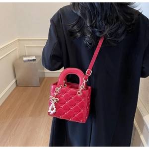 Détail du sac rouge matelassé avec rivets étoiles et breloque élégante en perles
