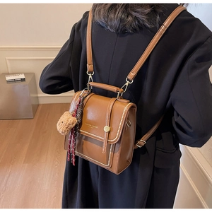 Rear view of a brown leather backpack with bear charm and stitching detail on blazer