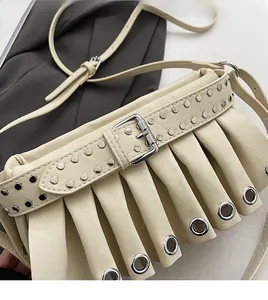 Detail of beige pleated shoulder bag with silver metal eyelets and studded strap