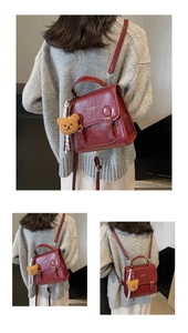 Detailed view of red vintage leather backpack with plush bear charm and metallic buckle