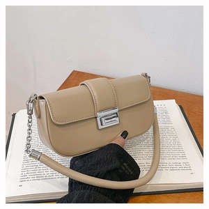 Detail of a beige leather shoulder bag with silver chain on an open vintage book