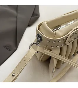 Close-up of beige underarm bag with silver rivets and high-quality metal hardware