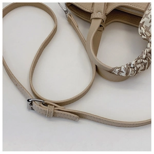 Detail of beige litchi leather handbag with houndstooth silk scarf and adjustable strap