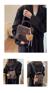 Detail of dark brown retro square bag showing top handle and adjustable straps with bear charm