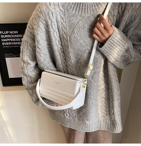 Minimalist white leather box bag worn by model with textured grey knit sweater