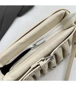 Detail of smooth silver zipper and metal eyelets on creamy white faux leather handbag