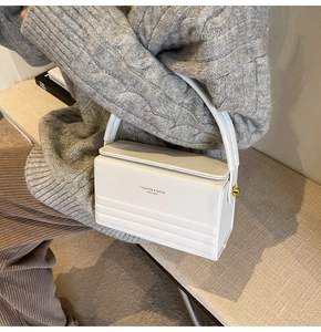 Detail of white box handbag with FASHION & BAGS lettering and gold hardware accents